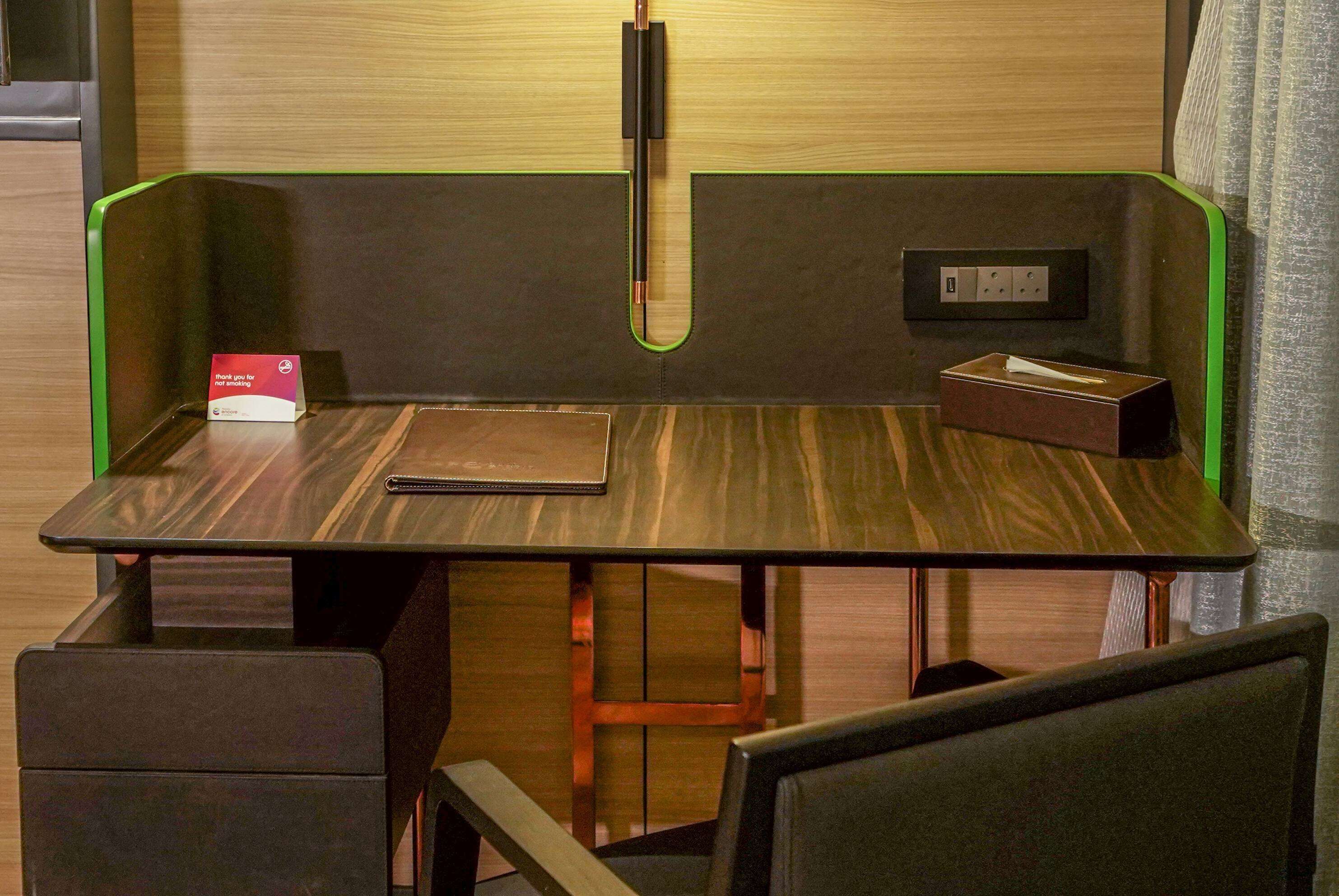 A modern workspace with a wooden desk, a notepad, a pen, and a tissue box.