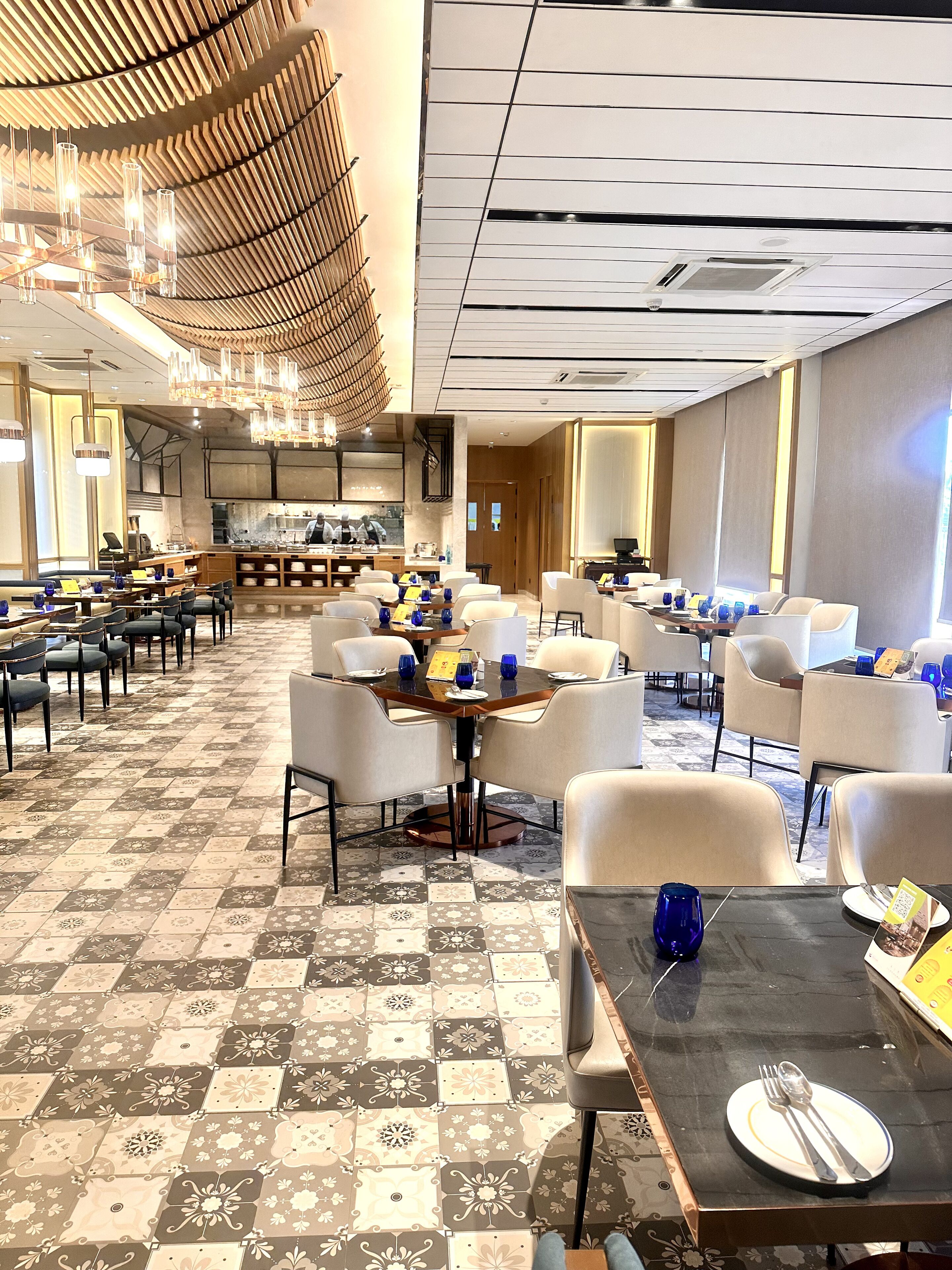 A spacious dining area with multiple tables and chairs, a central bar, and a patterned floor.