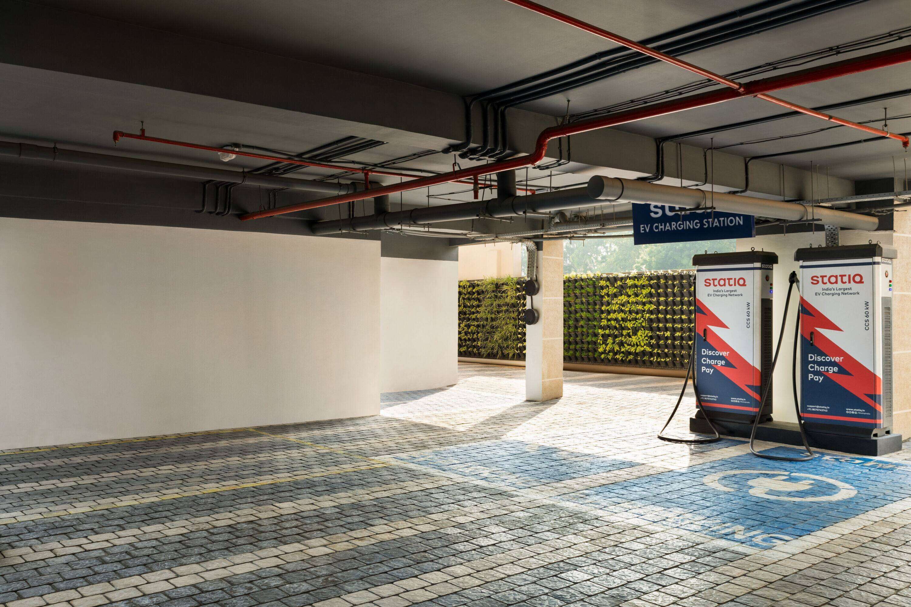 An indoor EV charging station area with tiled flooring and visible pipes on the ceiling.