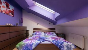 A bedroom with a skylight, a bed with floral bedding, a dresser, and a nightstand. - Cosy, sunny two-story apartment, 20min center (Hlavní mesto Praha)