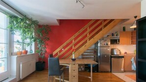 A kitchen with a wooden staircase, a dining table with chairs, and a refrigerator. - Cosy, sunny two-story apartment, 20min center (Hlavní mesto Praha)