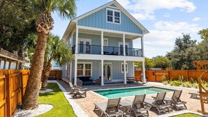 Una casa de dos pisos con balcón, piscina y patio.