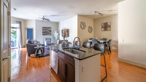 A spacious living area with a kitchen island, dining table, and chairs. There is a sofa and a coffee table in the living area.