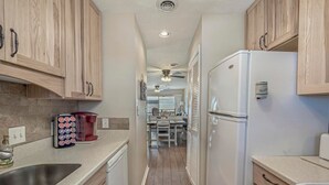 A narrow kitchen with wooden cabinets, a built-in oven, and a refrigerator.