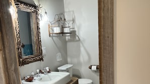 Un baño con un tocador de madera rústica, un espejo grande y un inodoro.