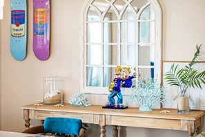 A wooden desk with a figurine, a glass jar with shells, and a blue plant.