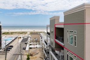 Un immeuble à plusieurs étages doté de balcons donnant sur une plage.