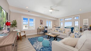 A spacious living room with a large window, a ceiling fan, and a view of the city. - Penthouse in Wildwood Crest- Best Views! (Wildwood)