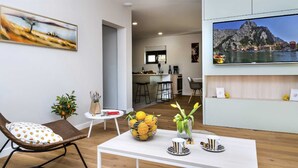 A modern living room with a dining area, a kitchen, and a TV displaying a scenic view. - Villa Luxury Dream in Omiš, indoor heated pool (Omiš)