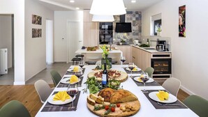 A modern dining area with a long table set for a meal, a kitchen in the background, and a dining area with a view of the kitchen. - Villa Luxury Dream in Omiš, indoor heated pool (Omiš)