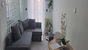 Una sala moderna con un sofá seccional gris, una pequeña mesa de comedor de madera y una orquídea en maceta.