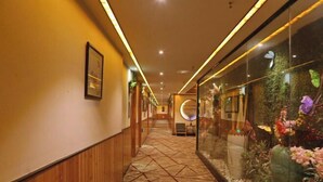 A hotel corridor with wooden paneling, patterned flooring, and a glass wall with floral decorations. - Rong'an International Hotel (Rong'an)