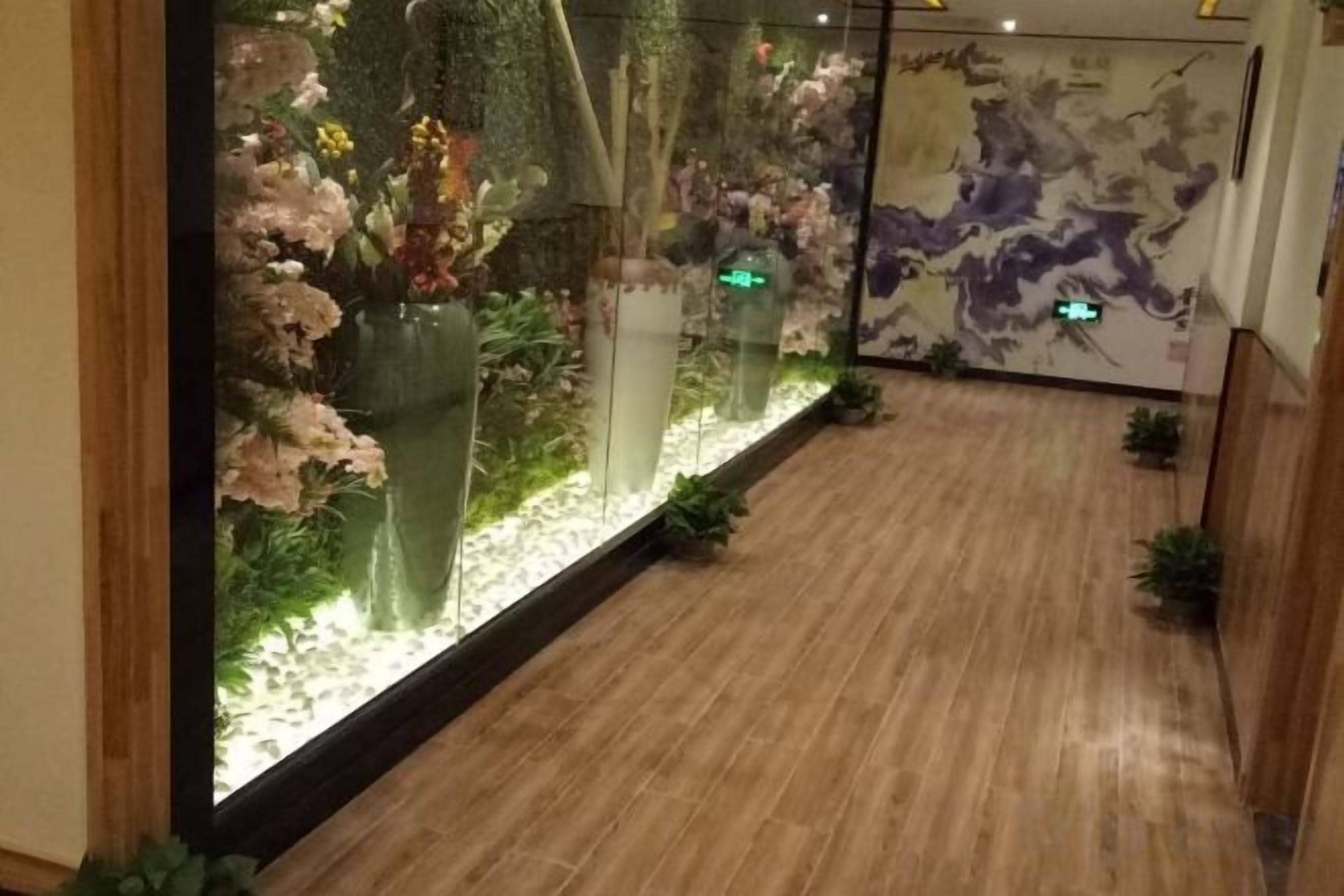 A hallway with a wooden floor, a glass display case with flowers, and a wall with a map.