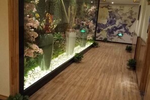 Un couloir doté d’un plancher en bois, d’une vitrine contenant des fleurs et d’un mur orné d’une carte.