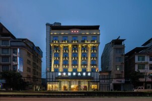 Un hotel de varios pisos con una entrada destacada, ventanas amplias y un balcón en el segundo nivel.