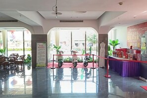 A hotel lobby with a reception desk, seating area, and a scooter parking area. - Rong'an International Hotel (Rong'an)