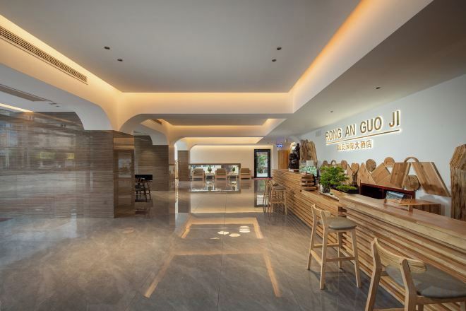 Eine moderne Hotelhalle mit einer Rezeption, einer Sitzgelegenheit und Blick in den Speiseraum.