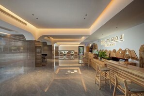 A modern hotel lobby with a reception desk, seating area, and a view into the dining area. - Rong'an International Hotel (Rong'an)