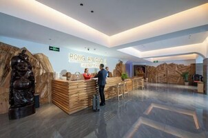 Zona de recepción con mostrador de madera, una recepcionista y un huésped.