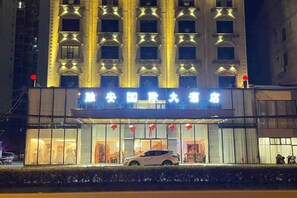 A hotel with a large sign, multiple floors, and a car parked in front. - Rong'an International Hotel (Rong'an)