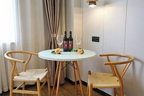 A small round table with two chairs, two bottles of alcohol, and two wine glasses on a white wall. - Rong'an International Hotel (Rong'an)