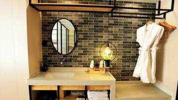 A modern bathroom with a large mirror, a sink, and a robe hanging on a rack.