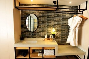 Un baño moderno con un espejo grande, un lavabo y una bata colgada en un perchero.