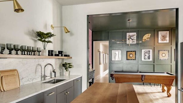 A modern kitchen with a wooden countertop, grey cabinets, and a pool table in the background. - King St. Manor | Luxury Penthouse - King St Views! (Charleston)