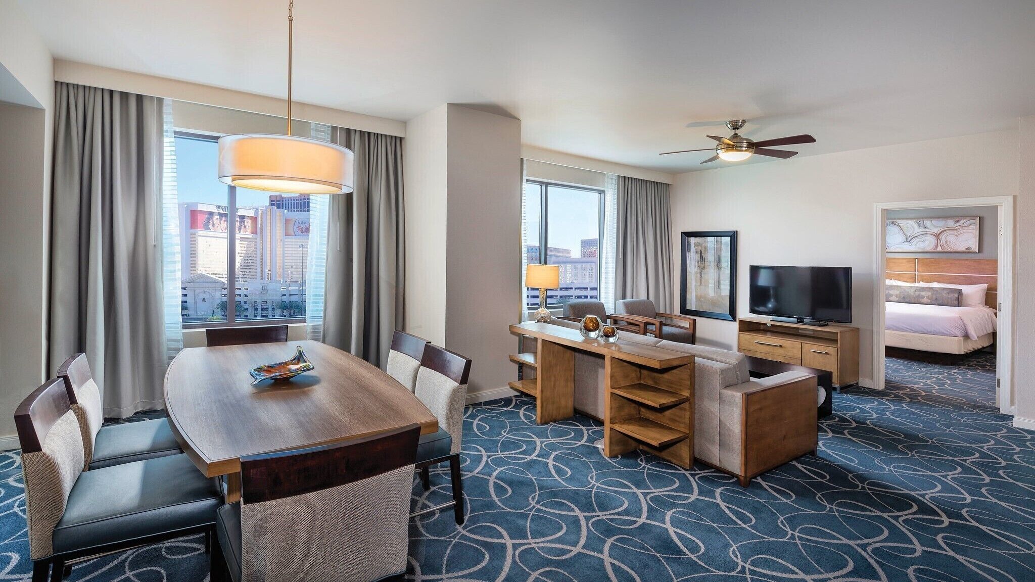 Une chambre d’hôtel comprenant un coin repas, une télévision, un lit et donnant sur la ville.