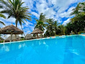 Una piscina al aire libre, sombrillas, sillones reclinables de piscina