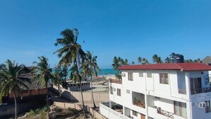 Zona residencial costera con palmeras, una playa y edificios con balcones.