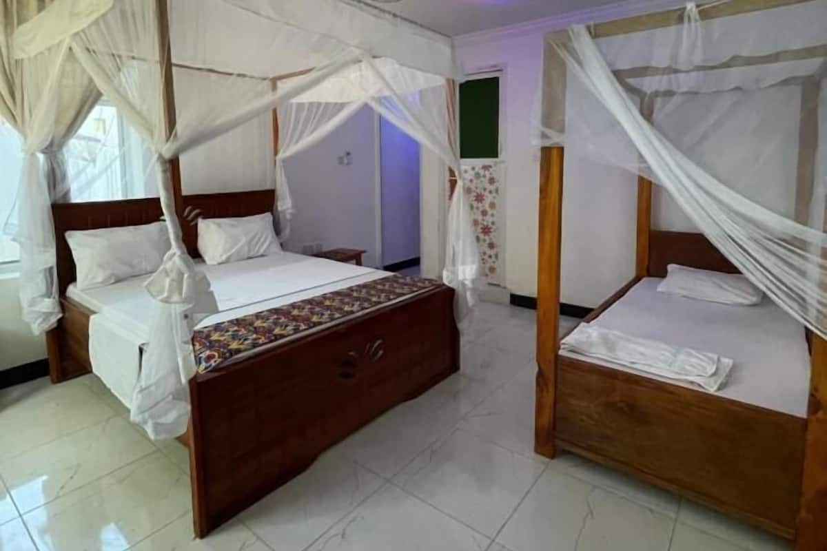 Una habitación con dos camas de madera, cada una con dosel, y un ventilador de techo.
