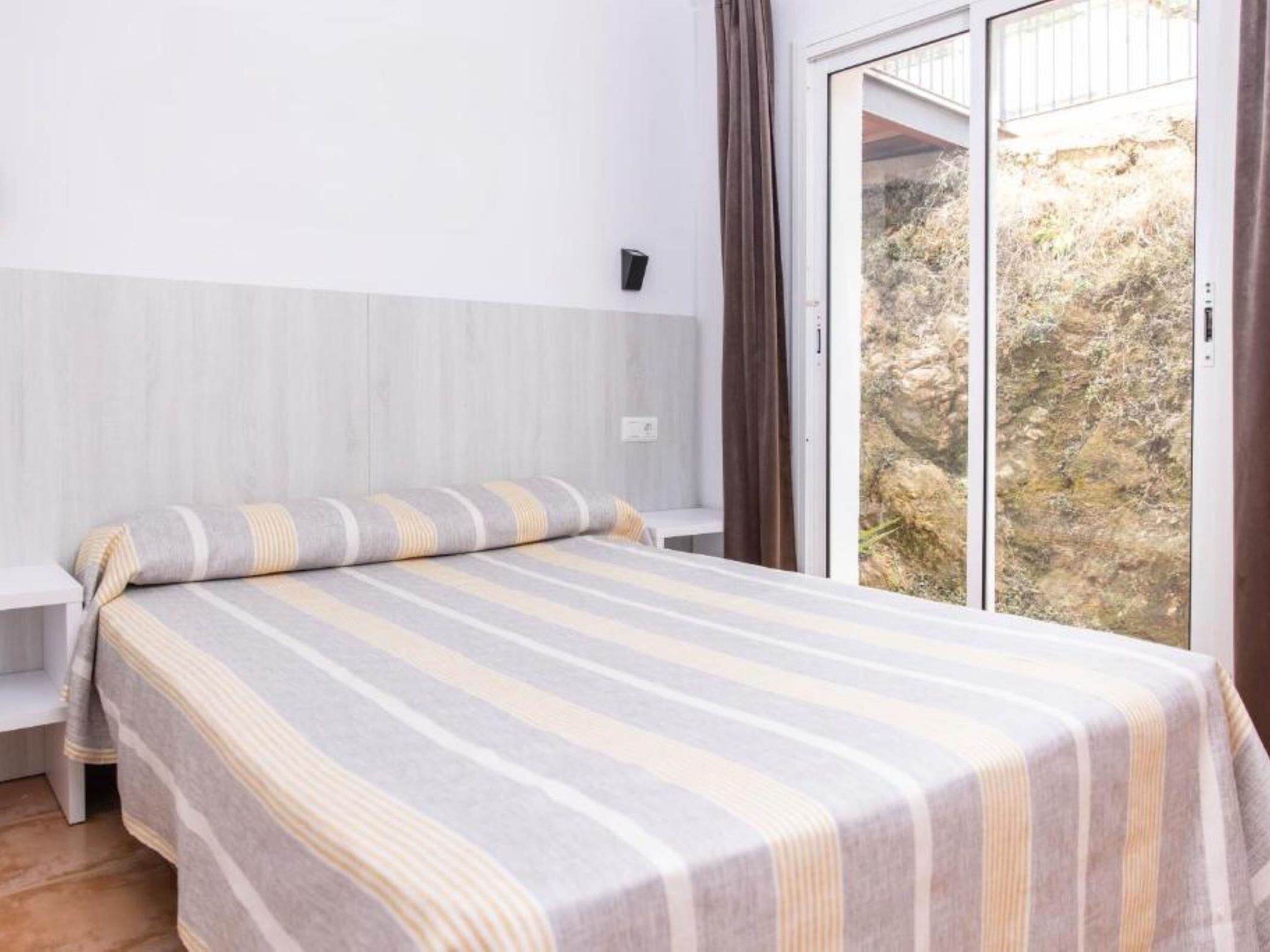A bedroom with a bed, a window, and a view of a rocky landscape.