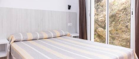 A bedroom with a bed, a window, and a view of a rocky landscape.