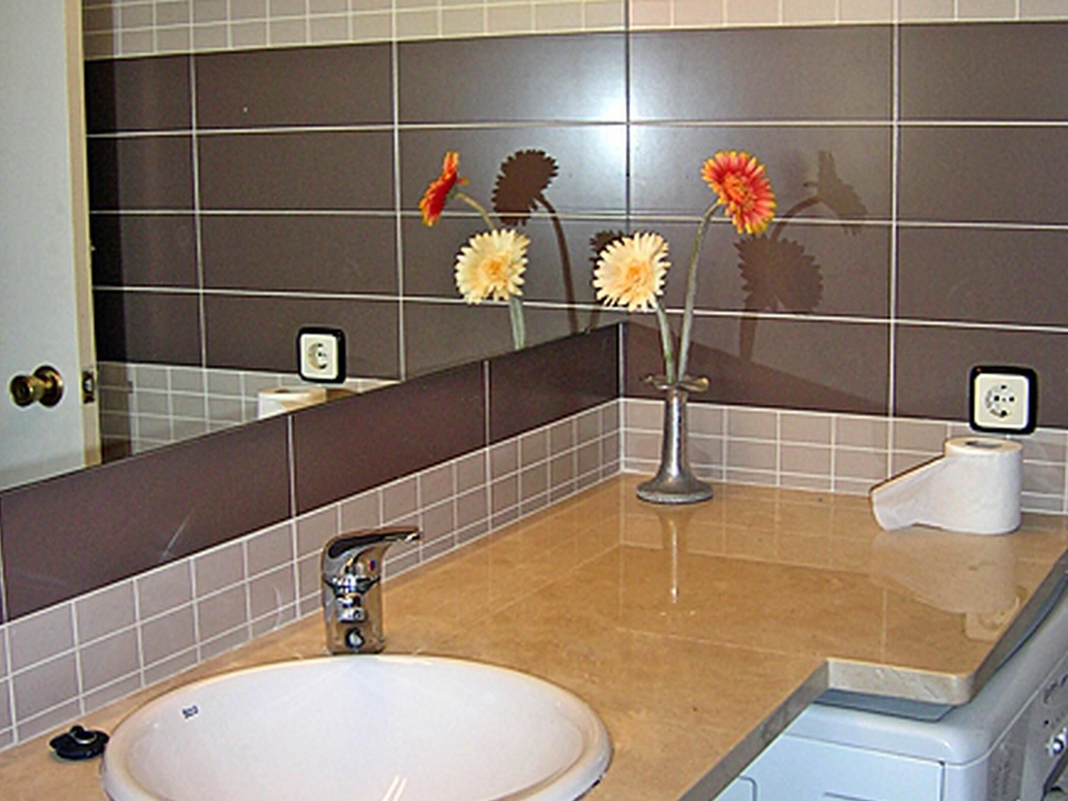 Ein Badezimmer mit Waschbecken, Spiegel und Toilettenpapierhalter.