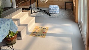 Ein Holzblockhaus-Innenraum mit einer Hängematte, einer kleinen Bank und einer Fußmatte.