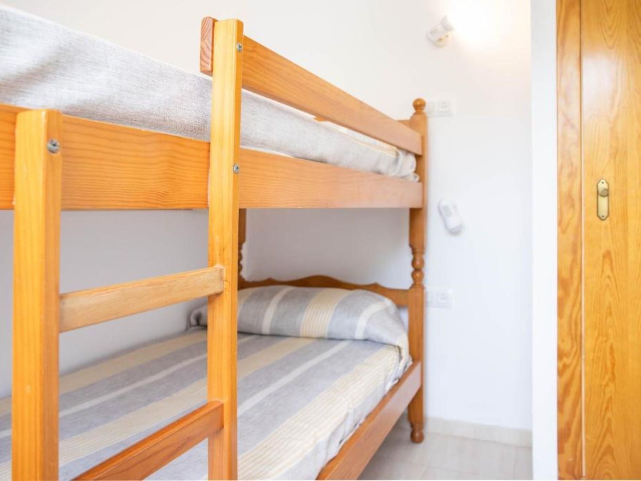 A bunk bed with wooden frames and striped bedding.