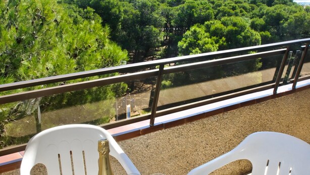 Een balkon met een tafel gedekt voor twee personen, inclusief een fles champagne en twee glazen.