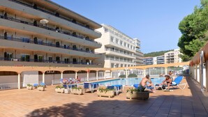 Un hôtel doté de nombreux balcons, d’une piscine et de chaises longues.