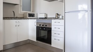 A kitchen with white cabinets, a microwave, a toaster, an oven, and a refrigerator.