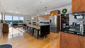 Una cocina moderna con una isla central, taburetes de bar y vistas amplias por los ventanales.