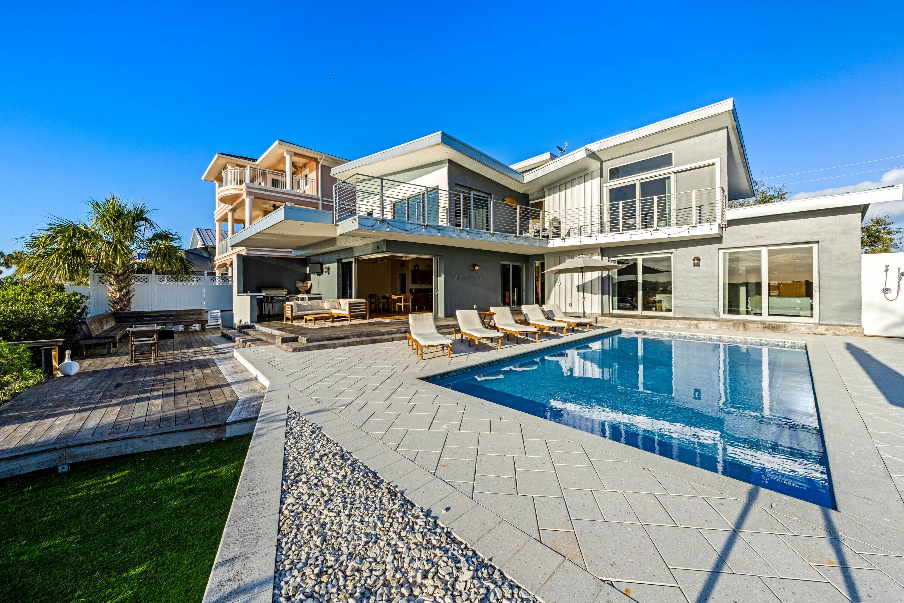 A modern two-story house with a swimming pool, outdoor seating, and a well-maintained lawn.