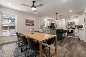 A modern kitchen with white cabinets, a wooden dining table, and a ceiling fan. - THE DULUTHIAN (Little Rock)