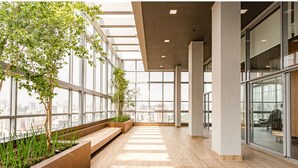 A spacious indoor area with large windows, wooden flooring, and planters with greenery. - Charlie Wide Pinheiros (São Paulo)