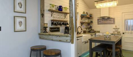 Una cocina con estanterías de madera, un candelabro y una zona de bar con taburetes.