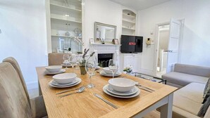 Un comedor con una mesa de madera dispuesta para cuatro personas, un televisor y una chimenea.