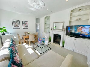 A living room with a fireplace, a television, and a dining area. - 3br Flat W. Rooftop Terrace in central hammersmith (London)