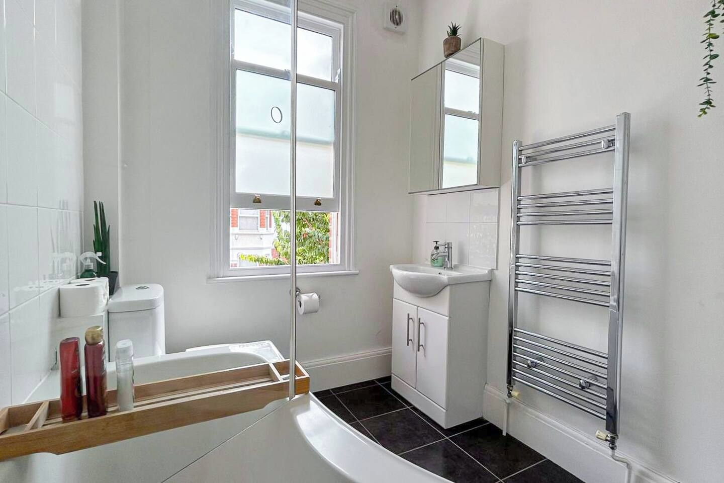 Ein Badezimmer mit einer Badewanne, einem Waschbecken, einem Spiegel und einem Handtuchhalter.