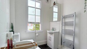 Un baño con bañera, lavamanos, espejo y toallero.
