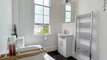 Ein Badezimmer mit einer Badewanne, einem Waschbecken, einem Spiegel und einem Handtuchhalter.